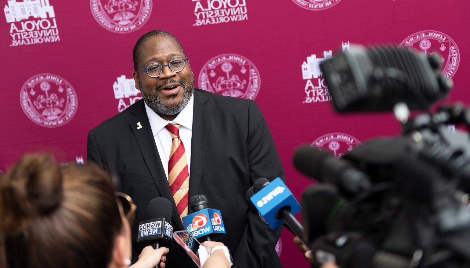 A crowd of reporters surround Dr. Cole in front of a Loyola backdrop.